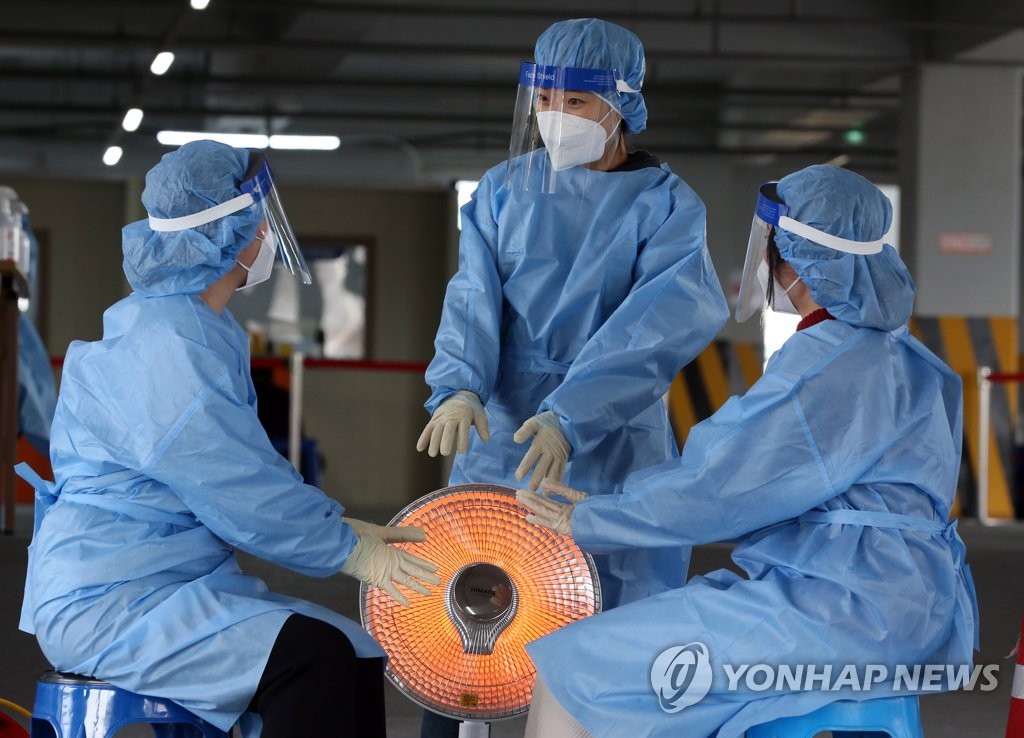 Medical workers at a makeshift clinic in Gwangju, 330 kilometers south of Seoul, gather around a heater on Nov. 5, 2020. (Yonhap)