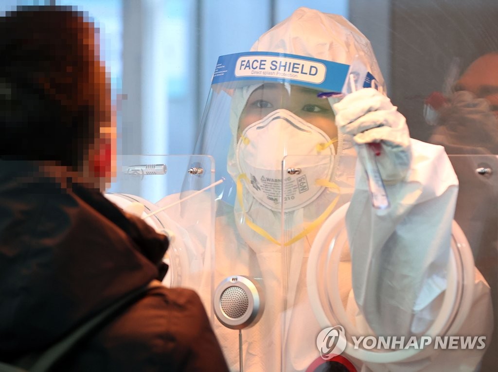 A health worker collects a specimen from a person for COVID-19 testing at a temporary screening station in Seoul on Feb. 3, 2021. (Yonhap)