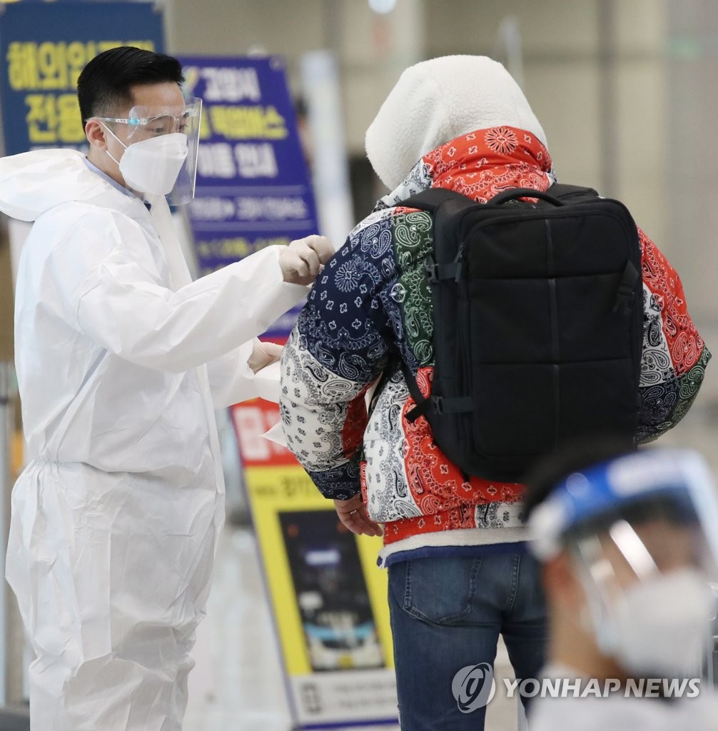 A quarantine official attaches a sticker to the shoulder of a passenger from abroad at Incheon airport, west of Seoul, on Feb. 8, 2021. (Yonhap)