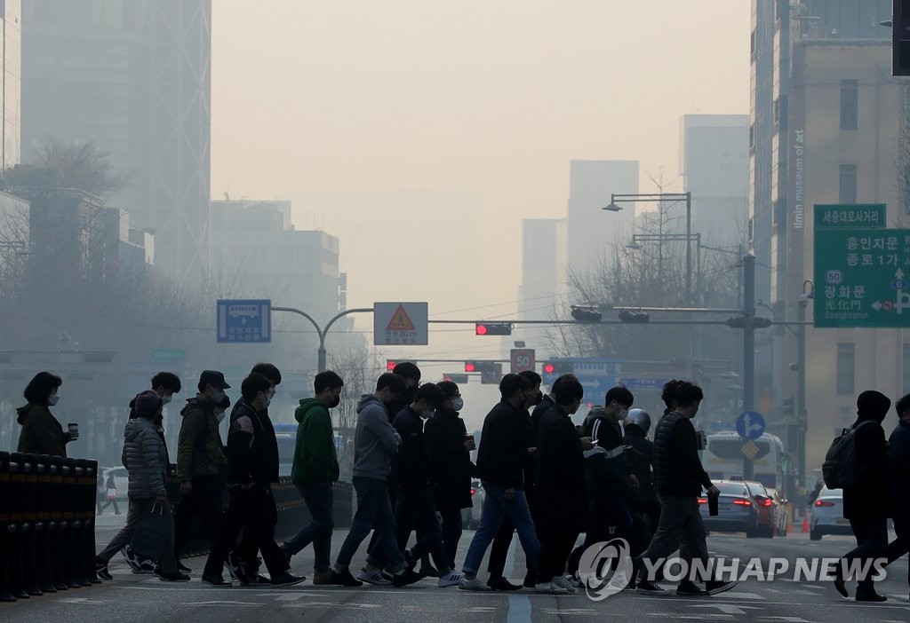 Masked people walk across a street in central Seoul during morning commute hours on March 11, 2021. (Yonhap)