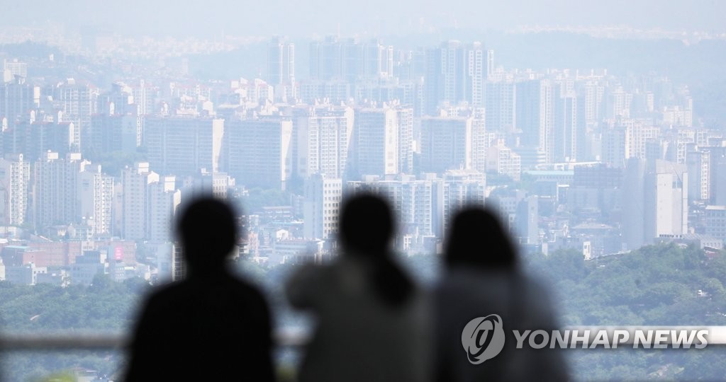 Des gens regardent des tours d'appartements du centre-ville de Séoul depuis le sommet du mont Namsan, le 4 juin 2021.