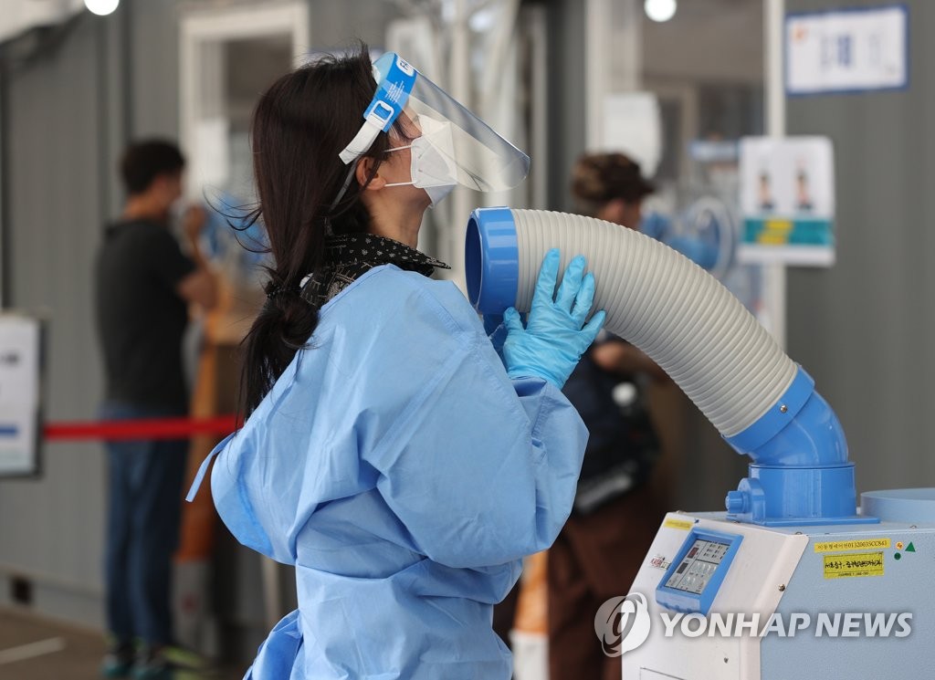 Une employée de la santé publique au centre de dépistage installé devant la gare de Séoul cherche à se rafraîchir, le vendredi 25 juin 2021. 