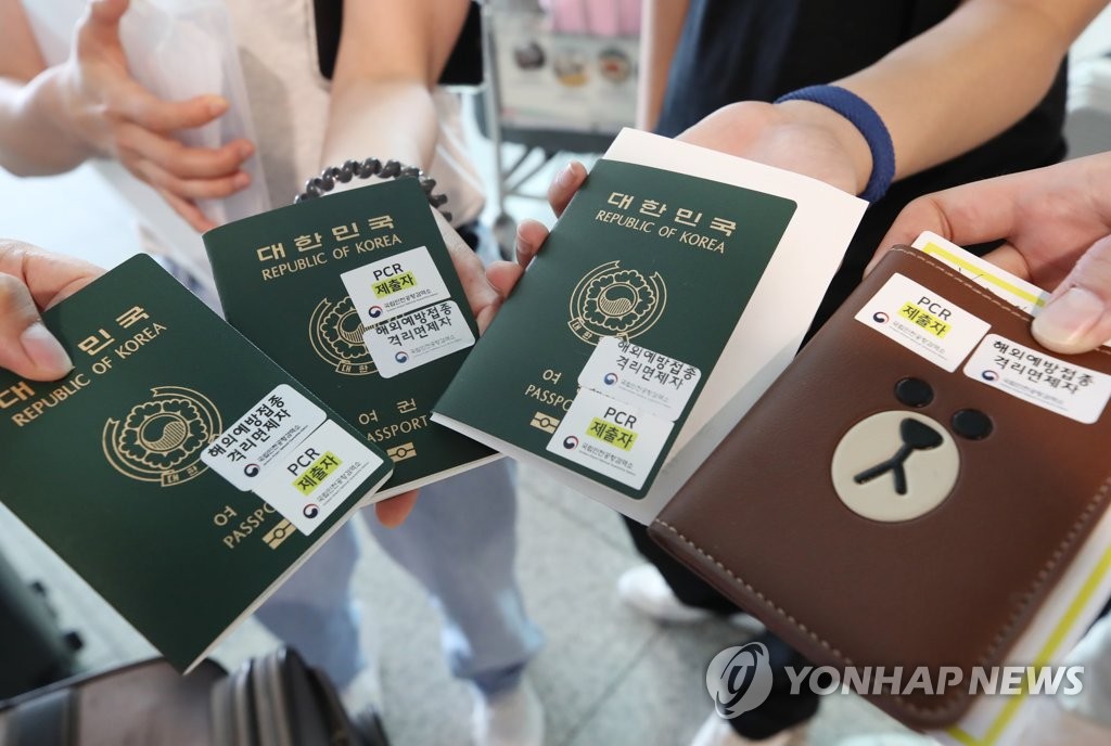 仁川国際空港で、陰性確認書を提出したことを示すシールなどを貼ったパスポートを見せる入国者＝（聯合ニュース）