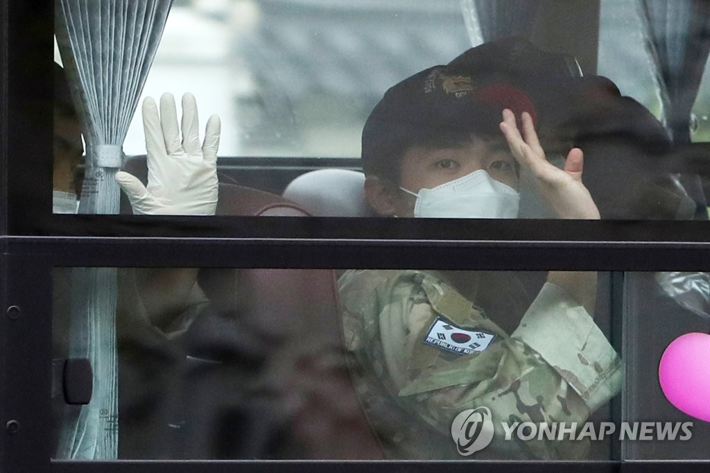 A member of the Cheonghae unit waves to the press from a bus at an air base in Seongnam, south of Seoul, on July 20, 2021. The 301-string unit on an anti-piracy mission off Africa was flown home after 247 members tested positive for COVID-19. (Yonhap)