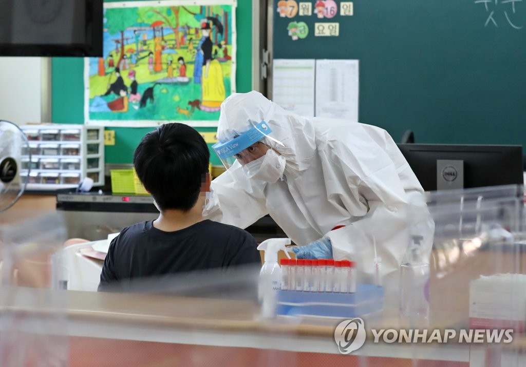 A medical staff member collects a specimen from an elementary school student for COVID-19 testing in a temporary screening station in the central city of Daejeon on July 22, 2021. (Yonhap)
