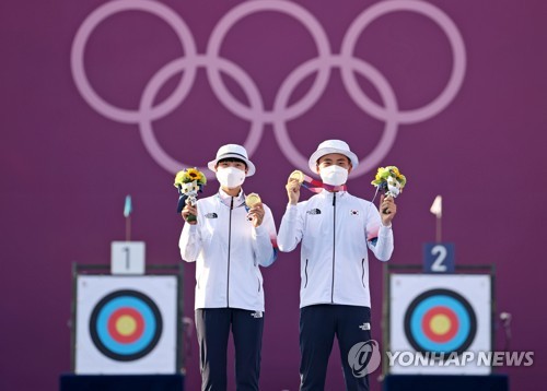 South Korean archers An San (L) and Kim Je-deok pose with their gold medals for the mixed team event at the Tokyo Olympics at Yumenoshima Park Archery Field in Tokyo on July 24, 2021. (Yonhap)
