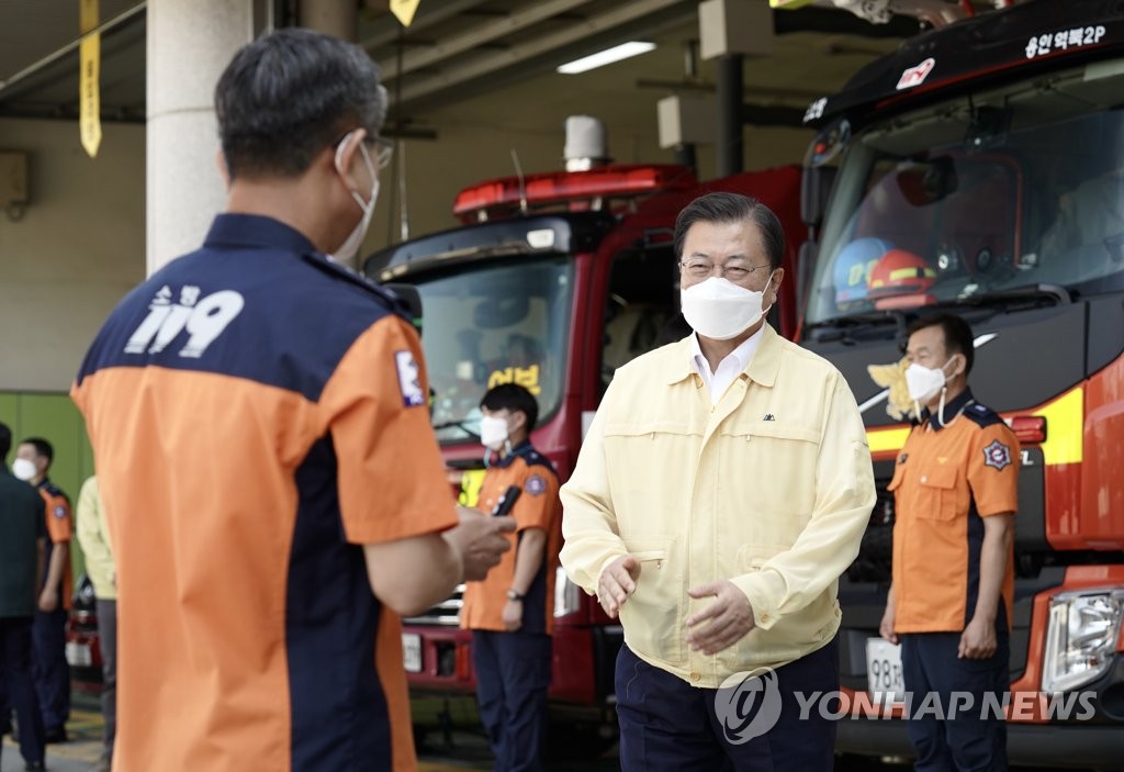 President Moon Jae-in wearing a yellow bomber jacket meets firefighters at the Yongin Fire Station in Gyeonggi Province on Aug. 6, 2021, in this photo provided by Cheong Wa Dae. (PHOTO NOT FOR SALE) (Yonhap)