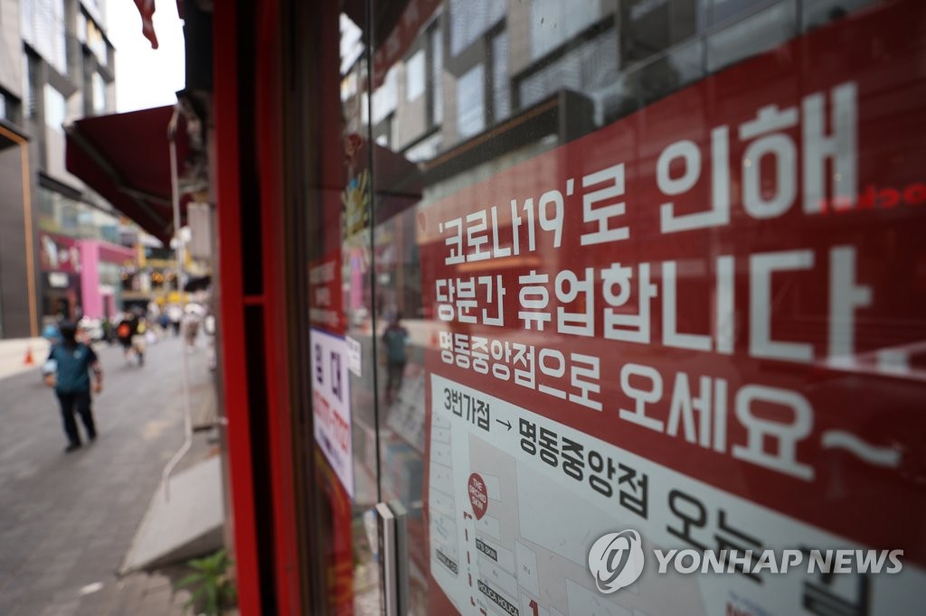 This file photo, taken Aug. 22, 2021, shows a sign about a temporary closure due to COVID-19 that was put up at a store in the shopping district of Myeongdong in central Seoul. (Yonhap)