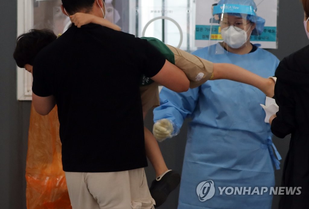 A citizen holds up his child at a makeshift clinic in central Seoul on Aug. 31, 2021. (Yonhap)