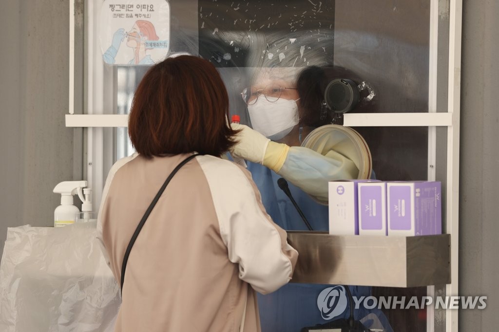 A health worker collects a sample from a citizen at a makeshift COVID-19 testing clinic in Seoul on Nov. 6, 2021. (Yonhap)