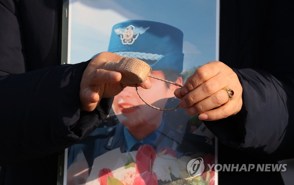 This file photo, taken Nov. 25, 2021, shows the mother of a deceased Air Force noncommissioned officer holding a picture of his daughter during a protest in Seoul. The officer took her own life in May after being sexually harassed by a colleague. (Yonhap)