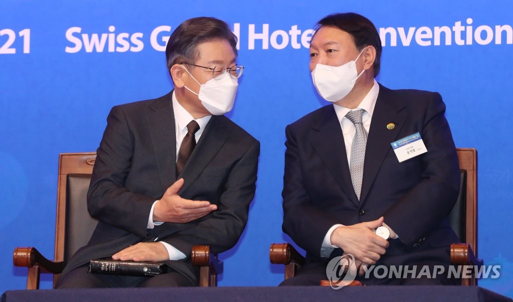 Lee Jae-myung (L), the presidential candidate of the ruling Democratic Party, and his main opposition People Power Party counterpart, Yoon Seok-youl, talk at the National Prayer Breakfast at a Seoul hotel on Dec. 2, 2021. (Pool photo) (Yonhap)