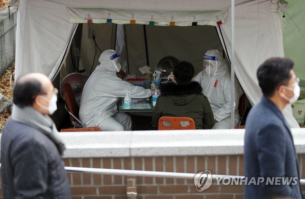 Health workers in protective gear conduct virus tests at a makeshift COVID-19 testing clinic in Daegu on Dec. 6, 2021. (Yonhap)