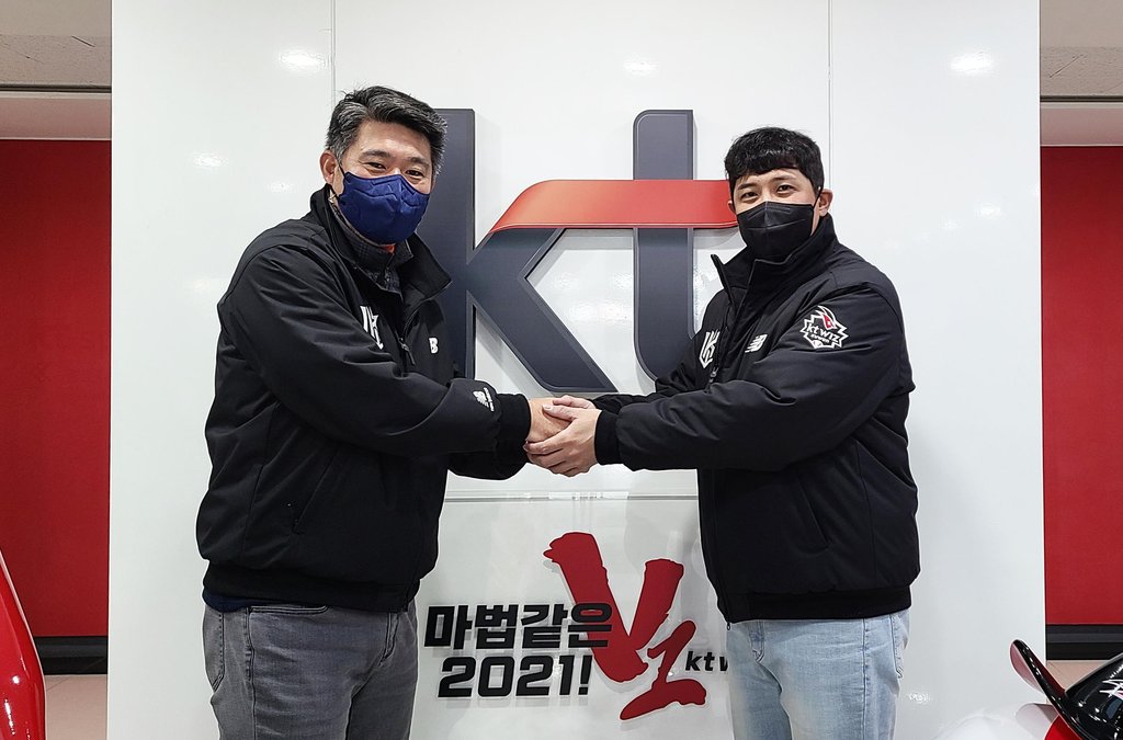 KT Wiz infielder Hwang Jae-gyun (R) shakes hands with the club's general manager, Lee Soong-yong, on Dec. 27, 2021, after signing a new four-year contract to stay put with the Korea Baseball Organization club, in this photo provided by the Wiz. (PHOTO NOT FOR SALE) (Yonhap)