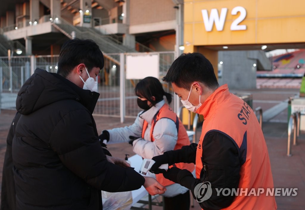 This photo taken on March 2, 2022, shows staff workers checking the temperature of people entering Jeonju World Cup Stadium in Jeonju, 243 kilometers south of Seoul. The government suspended the enforcement of the vaccine pass system from Tuesday. (Yonhap) 