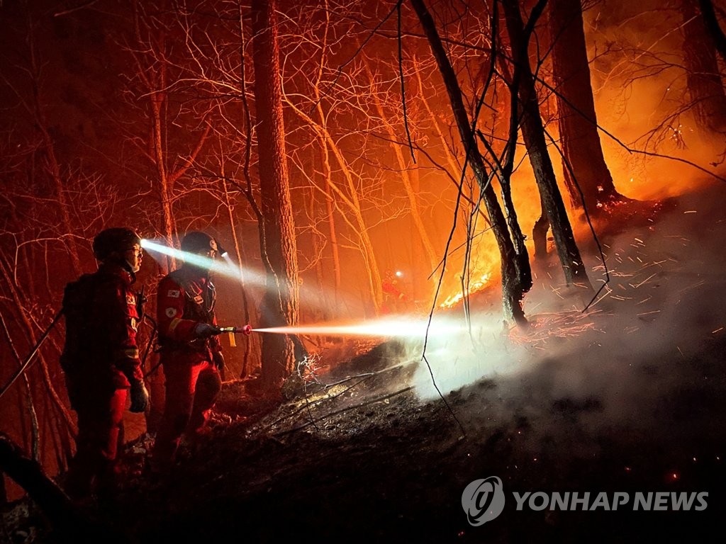 This image provided by forest authorities shows firefighters extinguishing a blaze in a pine tree forest in Uljin on March 10, 2022. (PHOTO NOT FOR SALE) (Yonhap) 