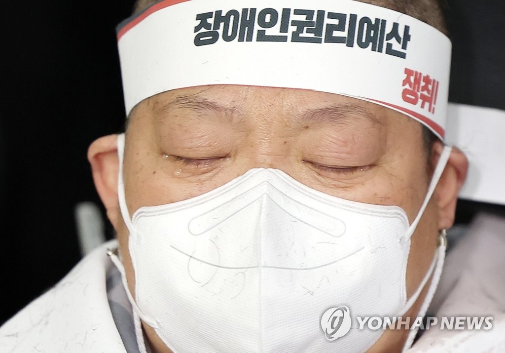 A wheelchair-bound female protester has her head shaven in a rally by the Solidarity Against Disability Discrimination (SADD) on March 30, 2022 at the Gyeongbokgung subway station in central Seoul. (Yonhap) 