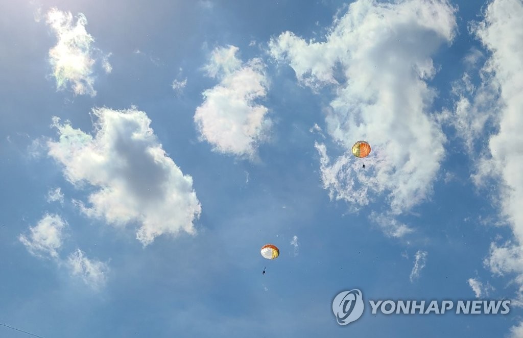 Pilots parachute down in the sky over a field in Sacheon, some 440 kilometers southeast of Seoul, on April 1, 2022, after a midair collision of two Air Force KT-1 trainer jets, in this photo provided by a reader. (PHOTO NOT FOR SALE) (Yonhap)