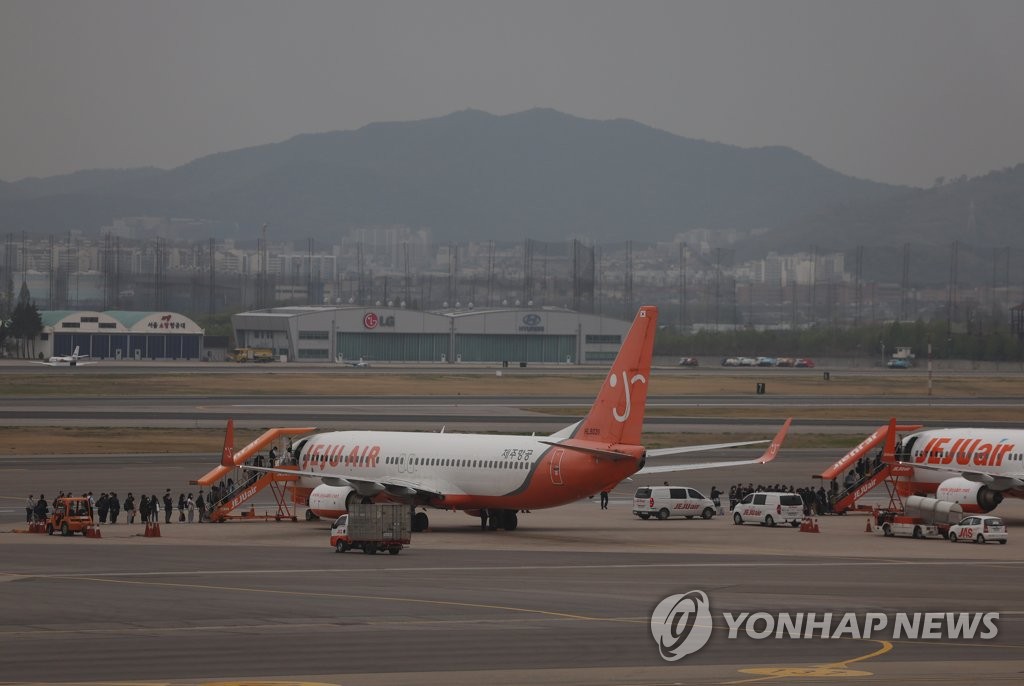 This file photo, taken April 22, 2022, shows people getting on a plane bound for the southern resort island of Jeju at Gimpo International Airport in western Seoul. (Yonhap)