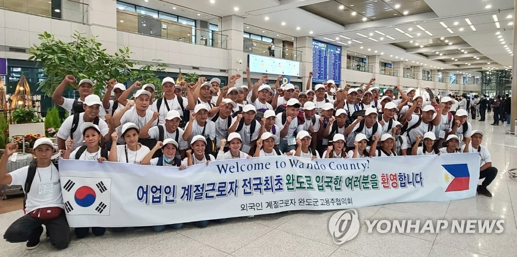 La foto muestra un grupo de trabajadores inmigrantes filipinos que llegaron a Corea del Sur, en abril, para un empleo temporal. 