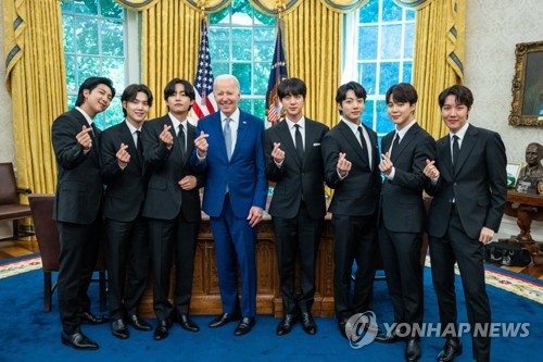 The members of K-pop sensation BTS make hearts with their fingers while posing for photos with U.S. President Joe Biden during their talks on anti-Asian hate crimes at the White House in Washington on May 31, 2022, in this photo provided by Big Hit Music. (PHOTO NOT FOR SALE) (Yonhap)