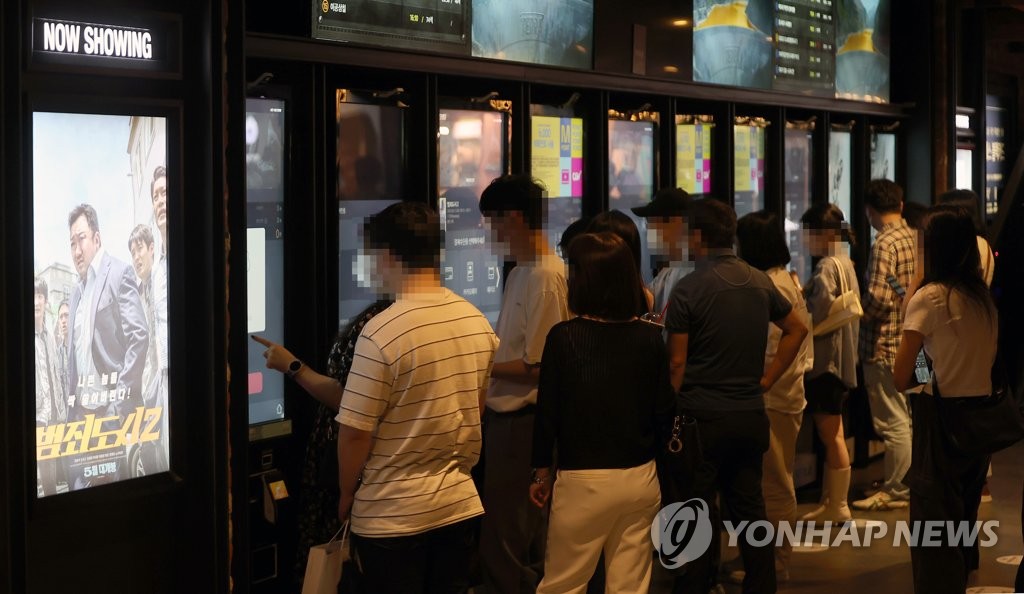 In this file photo taken on June 12, 2022, people buy tickets at electronic ticket booths in a movie theater in Seoul. (Yonhap)