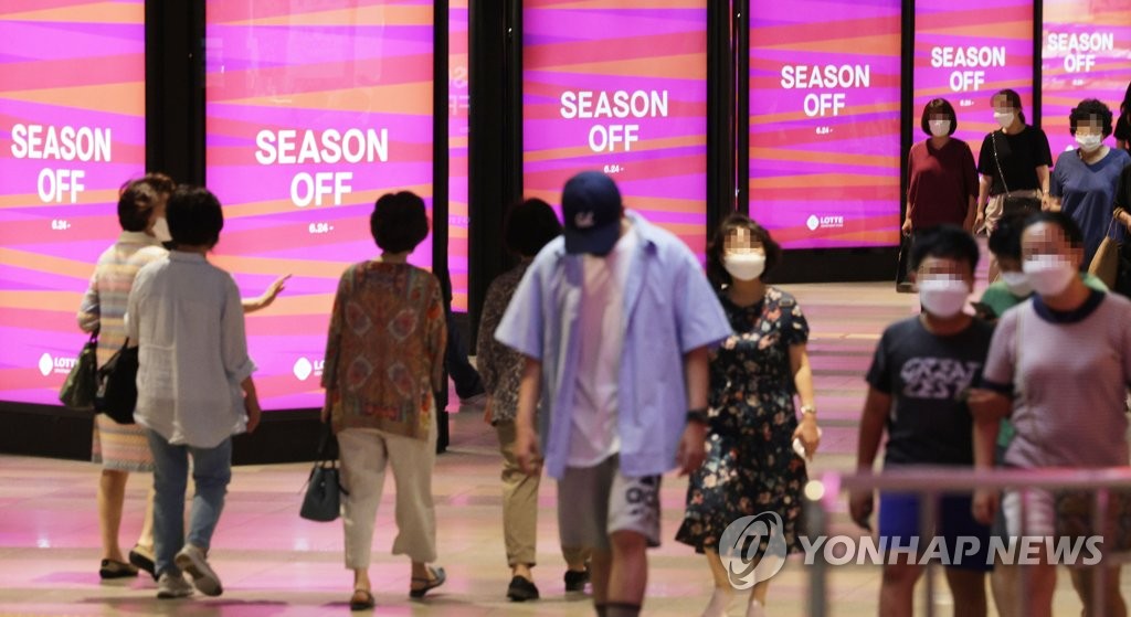 El 24 de junio de 2022, las personas caminan frente a los letreros electrónicos en unos grandes almacenes de Seúl.