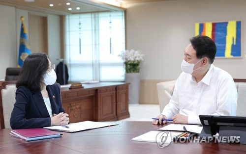 This photo, provided by the presidential office, shows President Yoon Suk-yeol (R) receiving a policy briefing from Gender Equality and Family Minister Kim Hyun-sook at his office in Seoul on July 25, 2022. (PHOTO NOT FOR SALE) (Yonhap)
