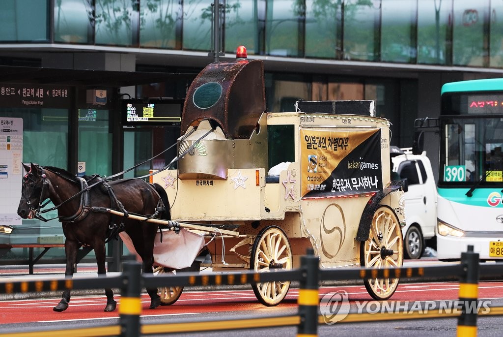 In this file photo, a horse-drawn carriage travels down the street in front of the office building of South Korean gaming company Kakao Corp. in Seongnam, south of Seoul, in protest of the company's purportedly poor management of mobile title "Uma Musume Pretty Derby" on Aug. 29, 2022. (Yonhap)