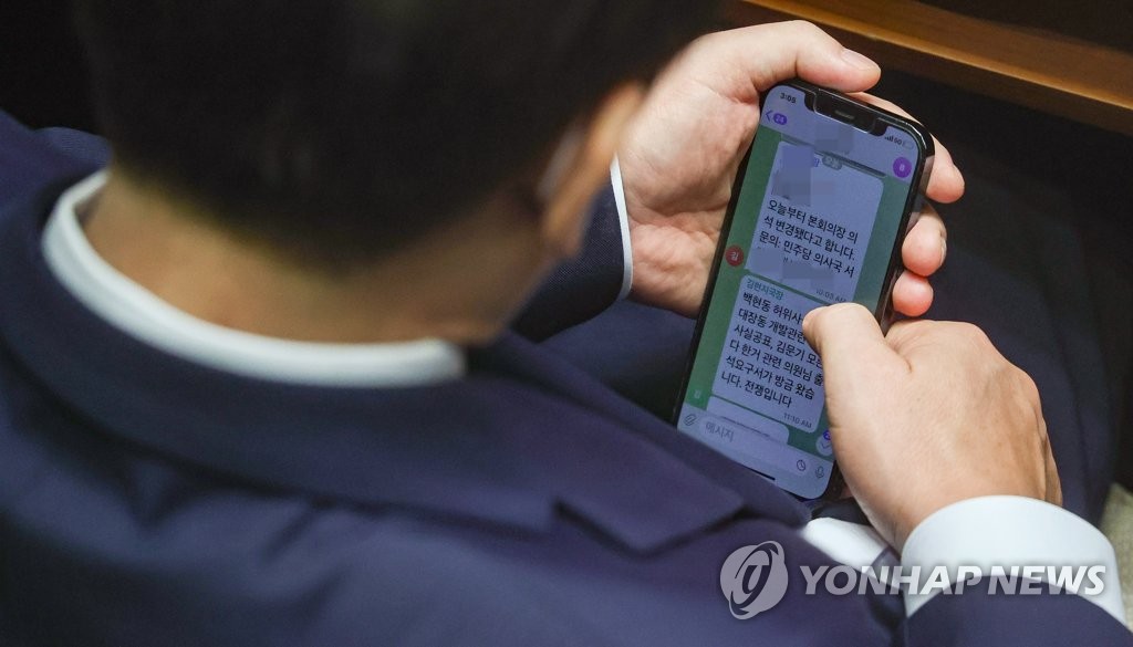 Main opposition leader Lee Jae-myung is caught on press cameras during a plenary session at the National Assembly in Seoul on Sept. 1, 2022, reading a text message from his aide telling him that the prosecution has notified him to appear for questioning. (Pool photo) (Yonhap)