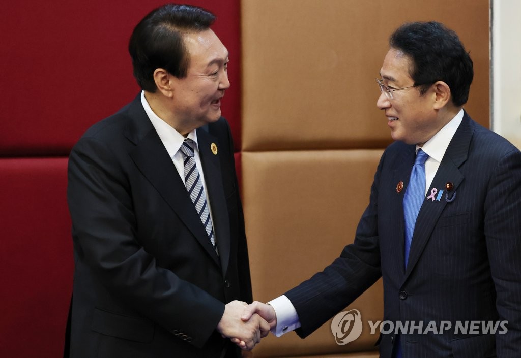 South Korean President Yoon Suk-yeol (L) shakes hands with Japanese Prime Minister Fumio Kishida during their summit at a hotel in Phnom Penh on Nov. 13, 2022. (Yonhap)