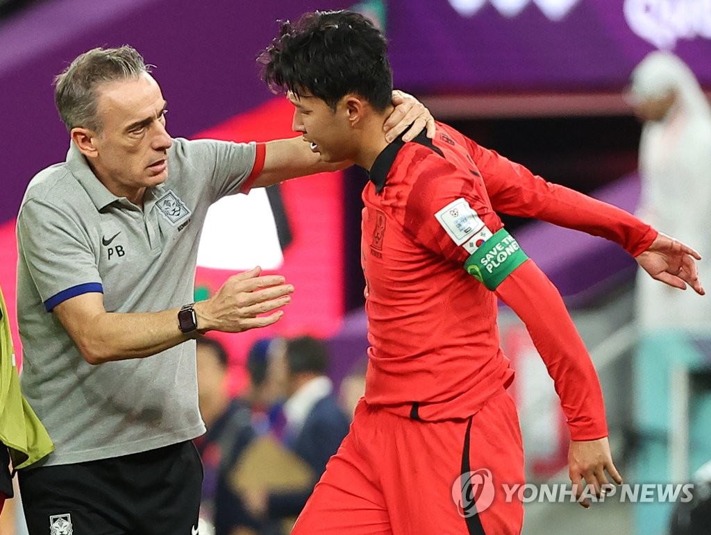 South Korea head coach Paulo Bento (L) tries to console his captain Son Heung-min following South Korea's 3-2 loss to Ghana in Group H at the FIFA World Cup at Education City Stadium in Al Rayyan, west of Doha, on Nov. 28, 2022. (Yonhap)