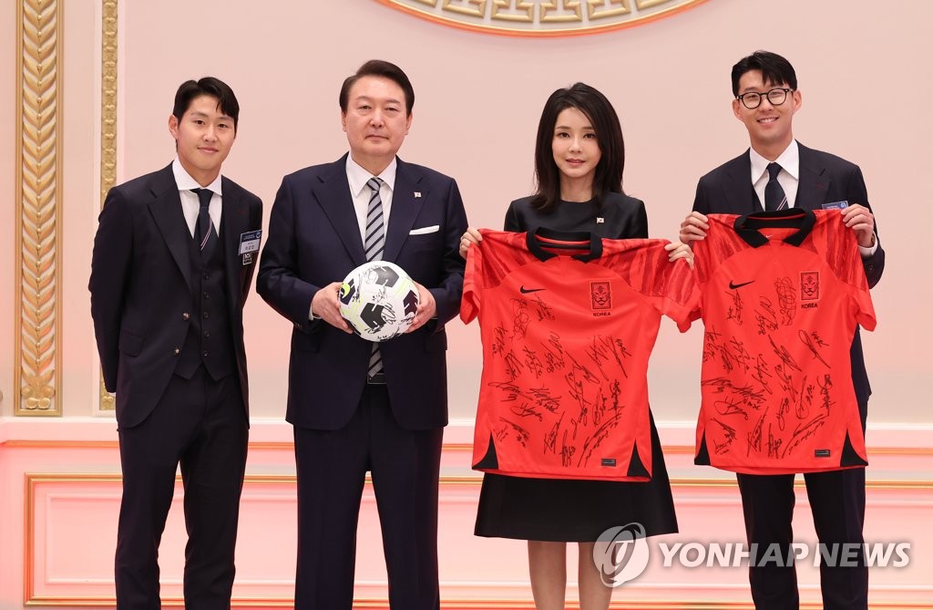 President Yoon Suk-yeol (2nd from L), first lady Kim Keon-hee (2nd from R), the national football team's captain Son Heung-min (R) and midfielder Lee Kang-in pose for a photo during a dinner Yoon hosted for the team at the former presidential compound of Cheong Wa Dae in Seoul on Dec. 8, 2022. The team presented the first couple with a football and team uniforms signed by the players. (Yonhap)