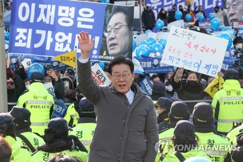 Supporters of Lee Jae-myung, leader of the main opposition Democratic Party, hold up a banner saying "Lee Jae-myung is not guilty" as he waves to them before entering the Seoul Central District Prosecutors Office on Jan. 28, 2023, for questioning in connection with a corruption-laden property development project in the city of Seongnam, south of Seoul, launched when Lee was mayor. (Yonhap)