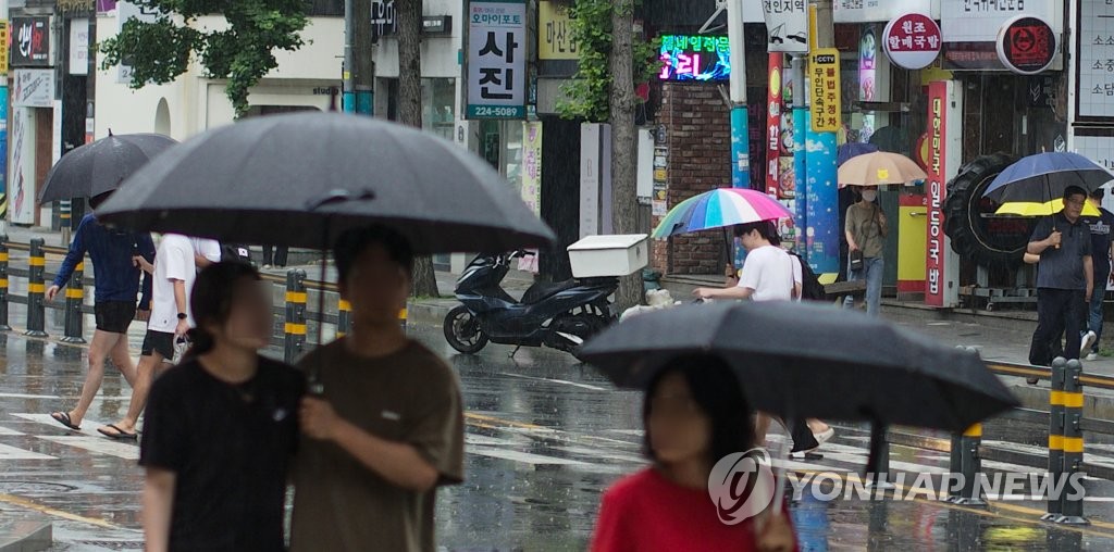 경남도가 장마철에 접어든 25일 오후 경남 창원시 마산합포구 한 거리에서 시민이 우산을 쓴 채 걷고 있다.  / 연합뉴스