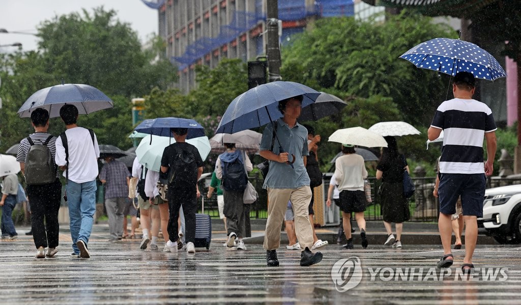 Personas con paraguas cruzan un paso de peatones en el centro de Seúl el 23 de julio de 2023, cuando se emitió una alerta de lluvia intensa para la ciudad capital.  (Yonhap)