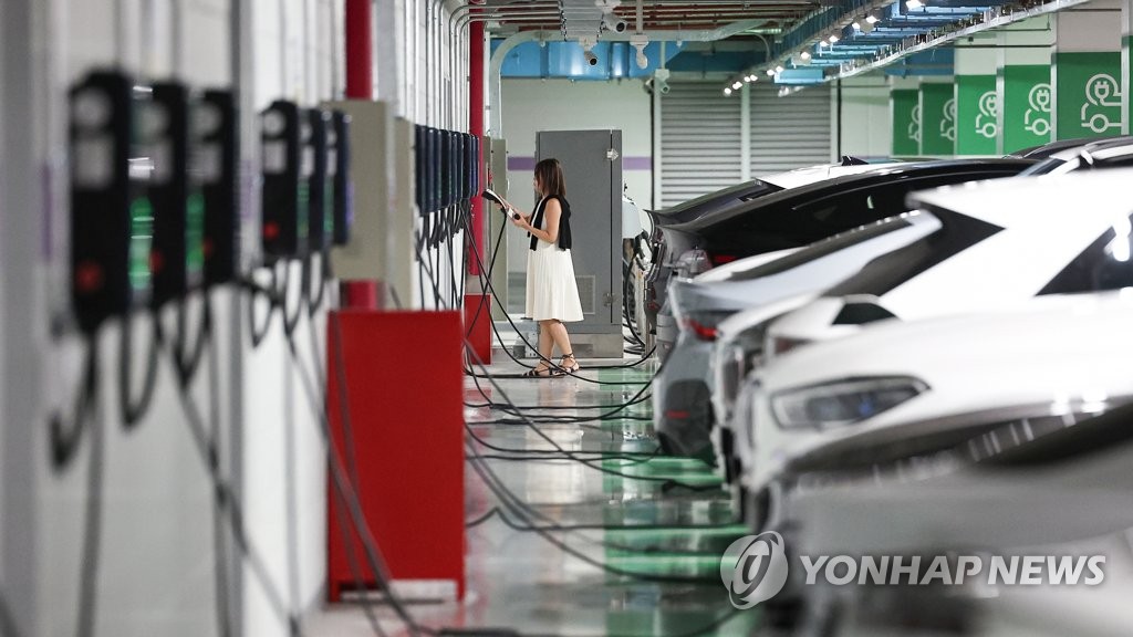 This photo taken Aug. 16, 2023, shows a woman charging her electric vehicle at a charging station in Seoul. (Yonhap)