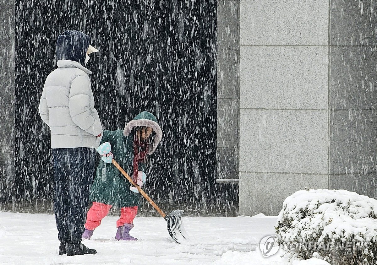 Un niño barre la nieve en Chuncheon, provincia de Gangwon, el 30 de diciembre de 2023. La agencia meteorológica estatal emitió un aviso de fuertes nevadas para partes de la capital y áreas circundantes más temprano ese día.  (Yonhap)