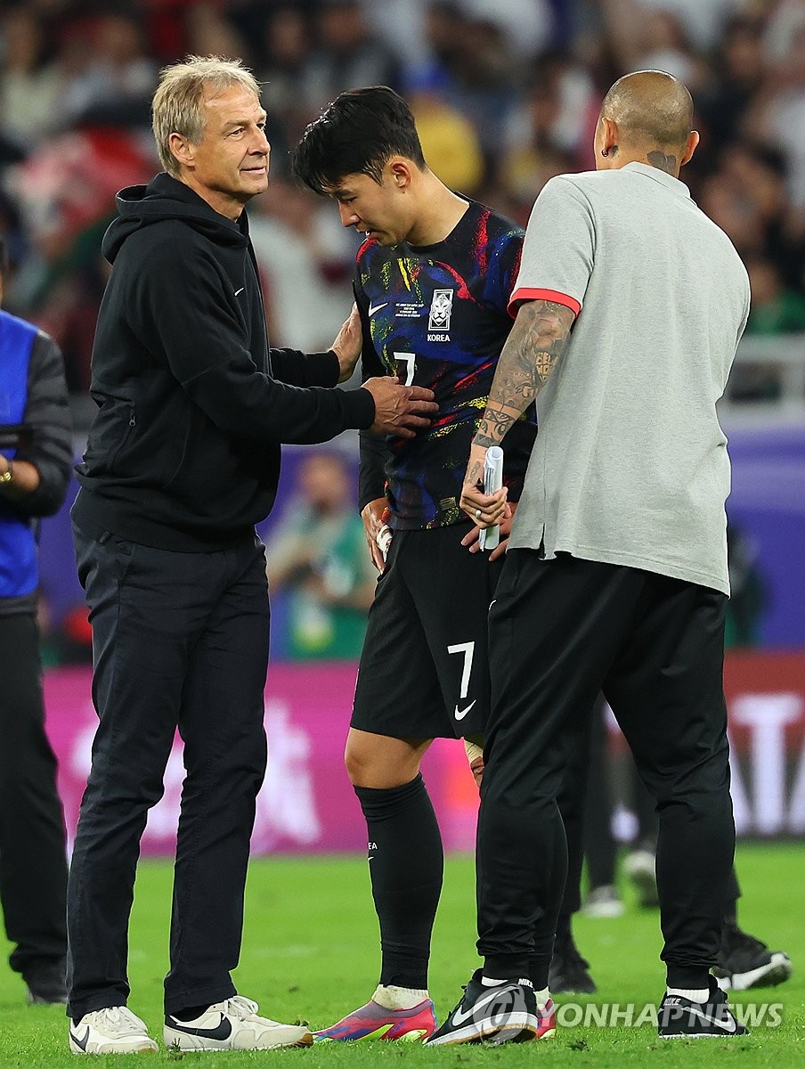 위르겐 클린스만 한국 감독(왼쪽)이 카타르 알라이얀의 아흐메드 빈 알리 스타디움에서 열린 아시안컵 4강전에서 요르단에 2-0으로 패한 뒤 팀 주장 손흥민(가운데)을 위로하고 있다.  2024년 2월 6일. (연합)