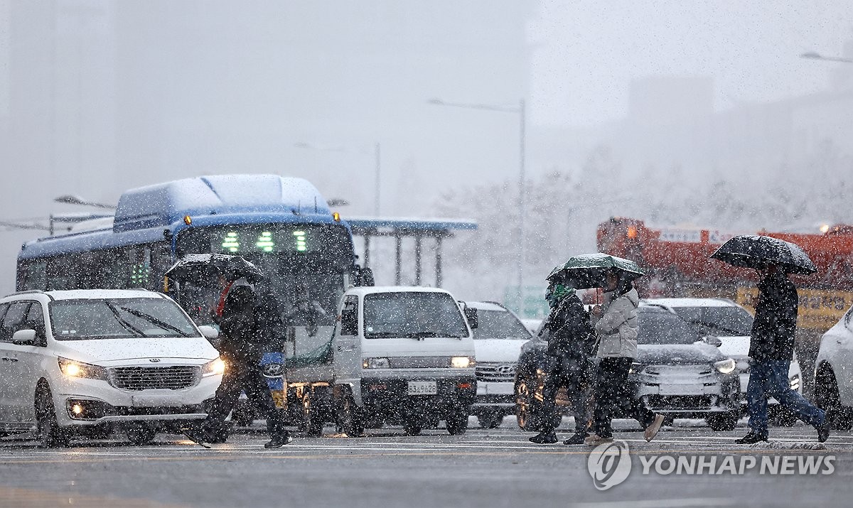 雪の中を歩く市民ら＝２７日、ソウル（聯合ニュース）