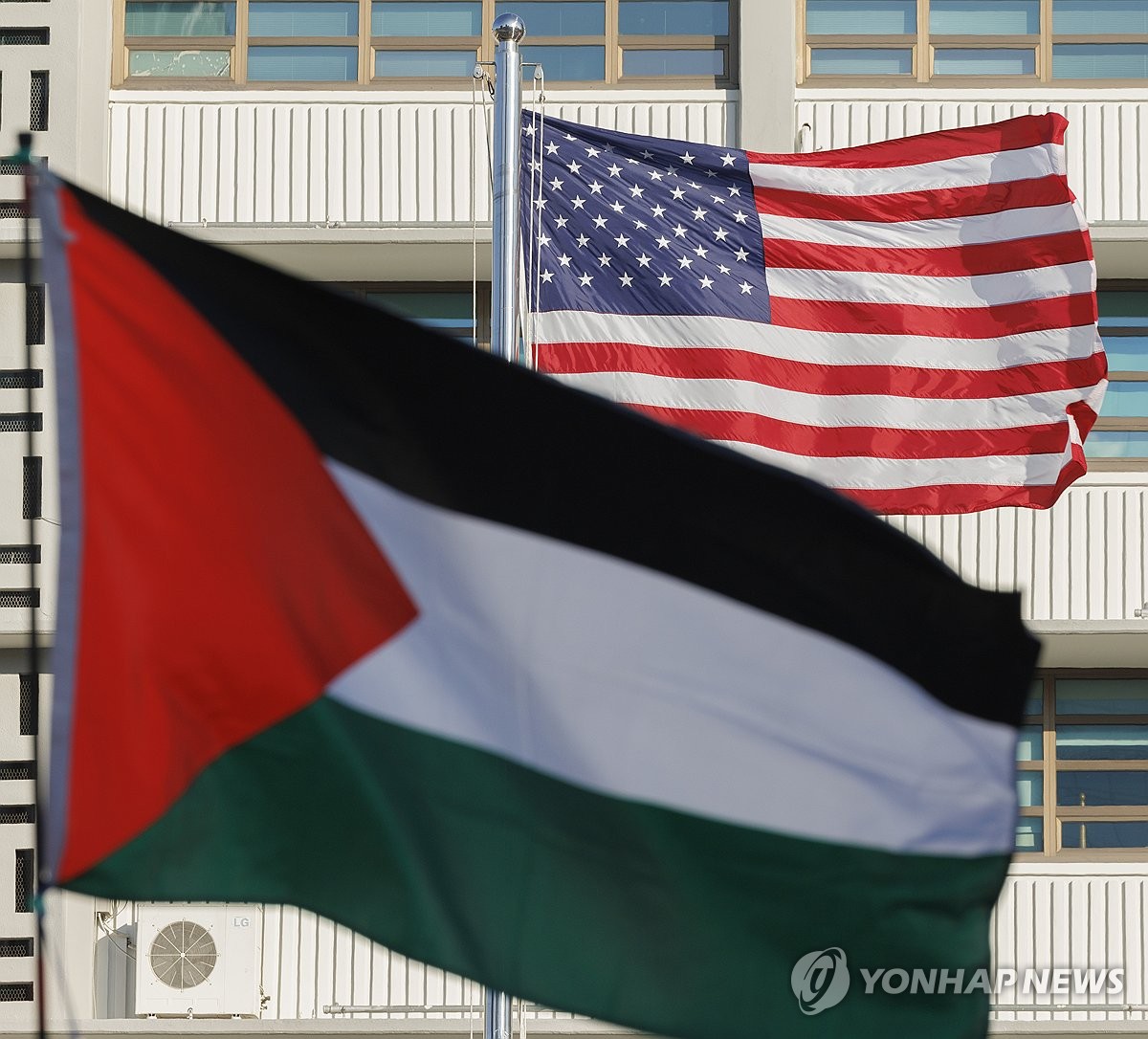 Esta imagen muestra la bandera nacional de Palestina en primer plano y la bandera de los Estados Unidos levantada durante una conferencia de prensa frente a la embajada de los Estados Unidos en el centro de Seúl el 5 de febrero de 2025, en la que los manifestantes denunciaron el plan de Franja Gaza del presidente Donald Trump. (Yonhap)