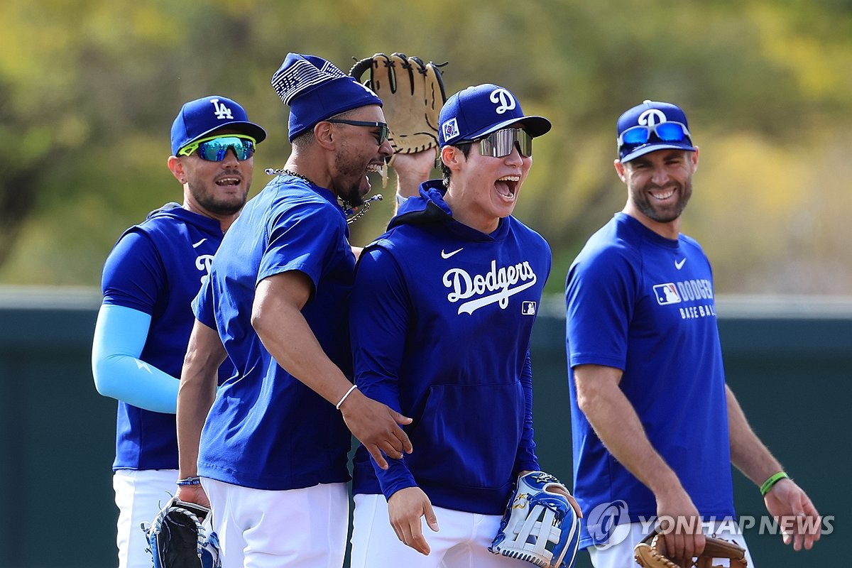 Kim Hye-seong of the Los Angeles Dodgers (2nd from R) shares a laugh with teammate Mookie Betts during spring training at Camelback Ranch in Glendale, Arizona, on Feb. 16, 2025. (Yonhap)