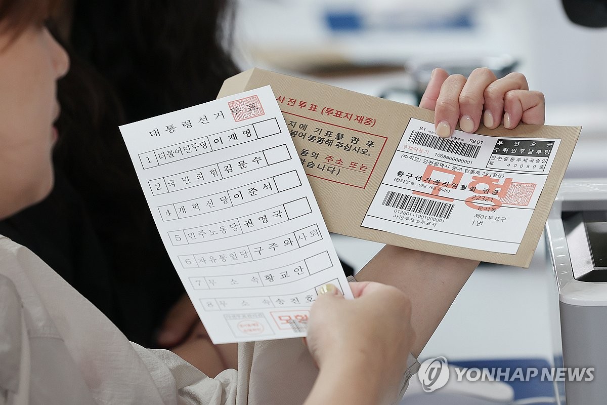 仁川空港の期日前投票所で投票用紙と不在者投票のための転送用封筒をみせる関係者＝（聯合ニュース）